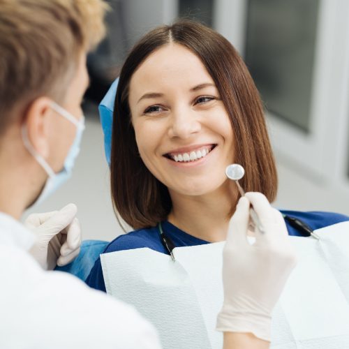 Male Professional Dentist With Gloves And Mask And Discuss What The Treatment Will Look Like Of The Patient's Teeth. Discussion Of The Treatment Plan And Healthy Smile